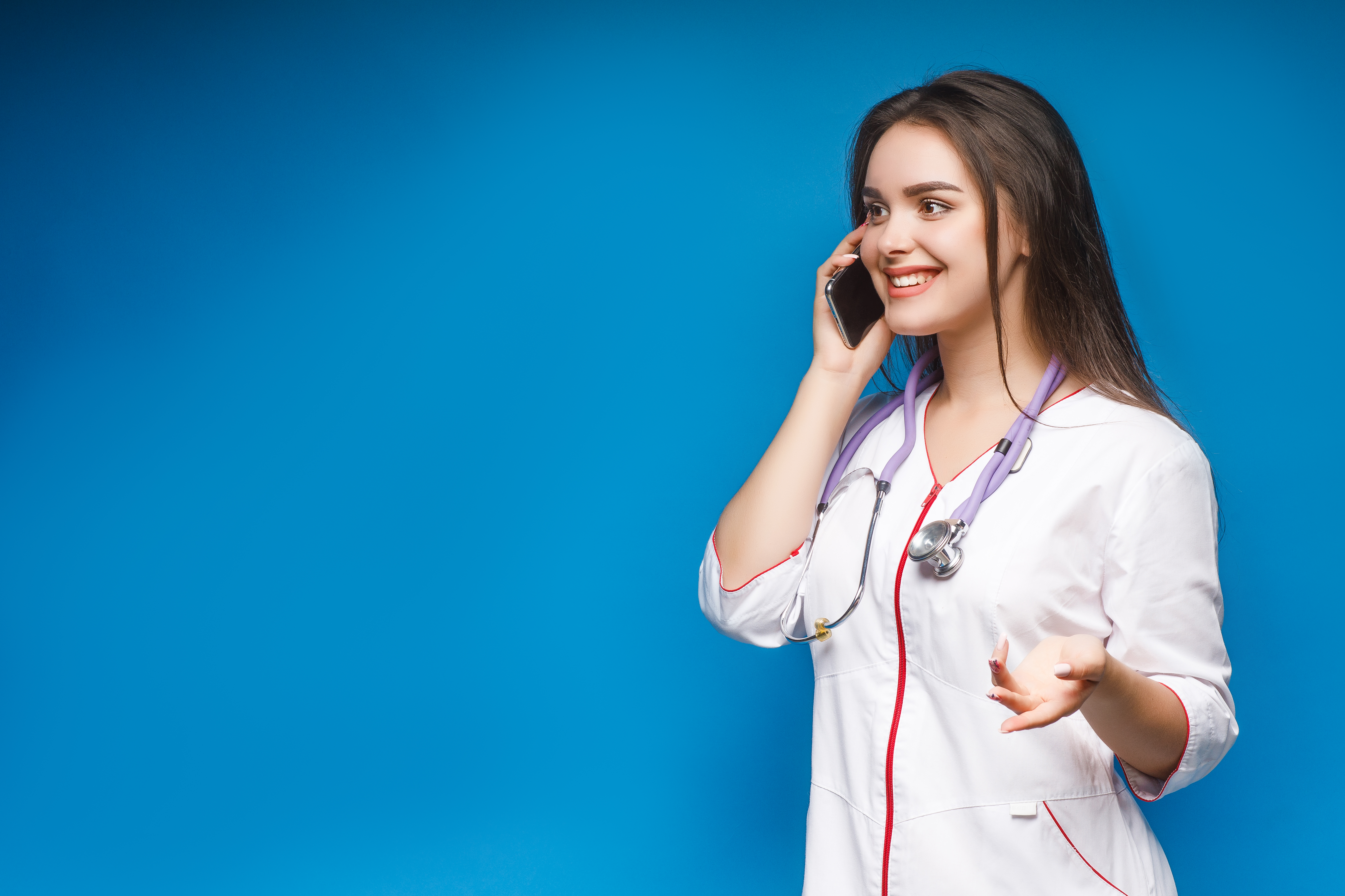 young-gorgeous-doctor-talking-by-phone-with-patient-on-blue-background